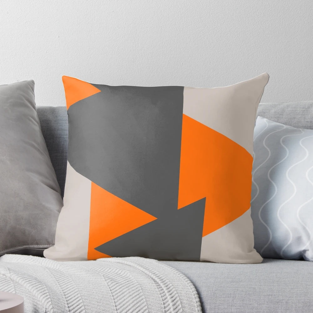 Close-up of a decorative throw pillow featuring a modern, minimalist pattern of orange and grey triangles.