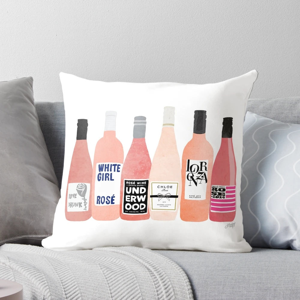 Rose-themed decorative pillow with bottles and wine glasses on a white background