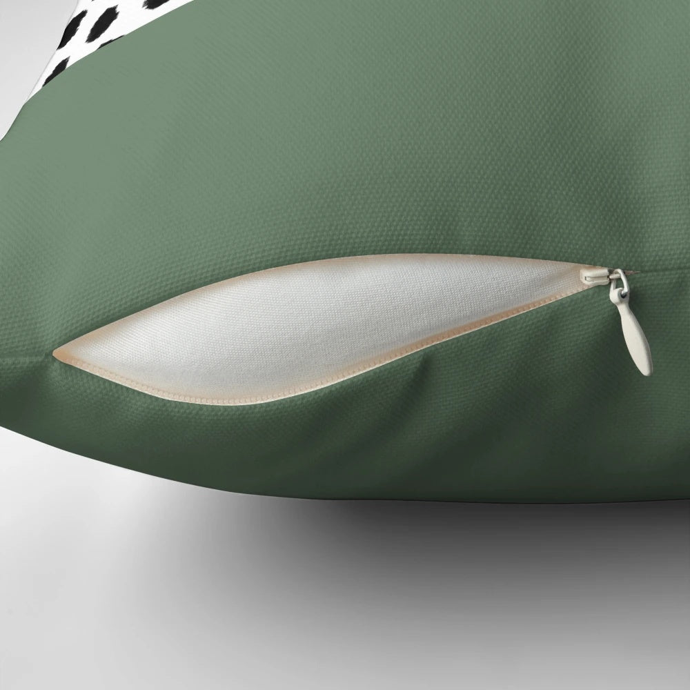 Decorative accent pillow featuring a bold dalmatian spots print in shades of sage green, black, and white.