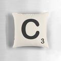 A decorative throw pillow featuring a Scrabble-style letter 'C' in a bold, retro typeface.