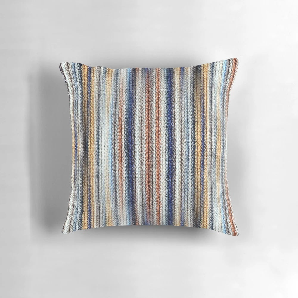 A stylish, striped, knitted, geometric pillow in shades of blue, white, and brown.
