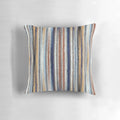 A stylish, striped, knitted, geometric pillow in shades of blue, white, and brown.