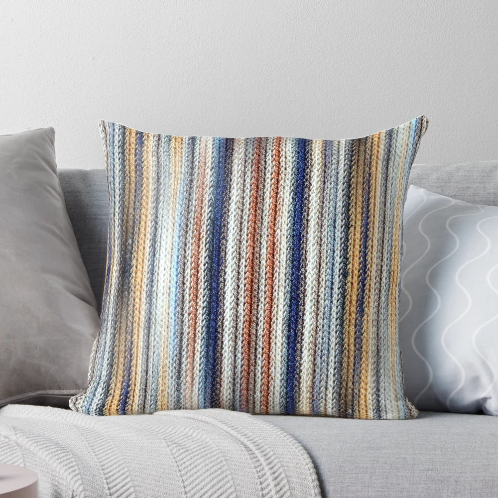 A stylish, striped, knitted, geometric pillow in shades of blue, white, and brown.