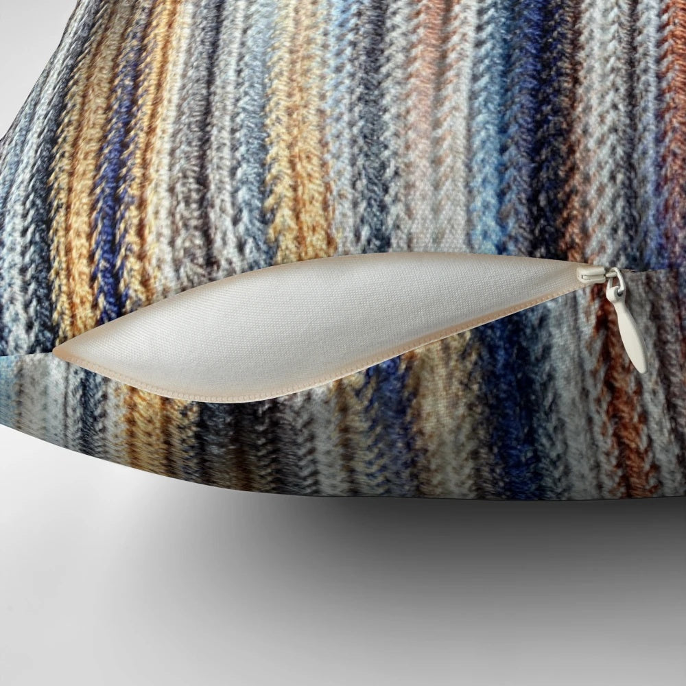 A stylish, striped, knitted, geometric pillow in shades of blue, white, and brown.