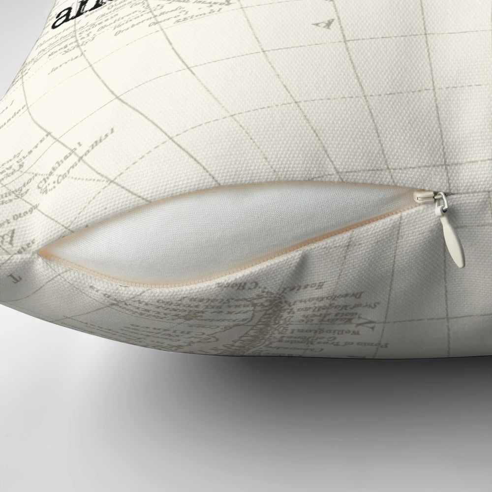 Vintage world map design printed on a cream-colored pillow with black and white typewriter-style typography
