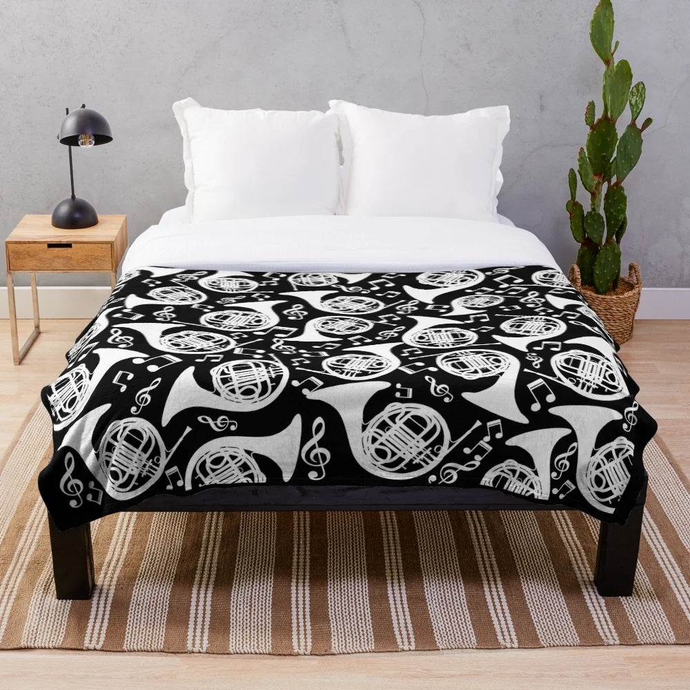 White plush blanket featuring a pattern of french horns and music notes