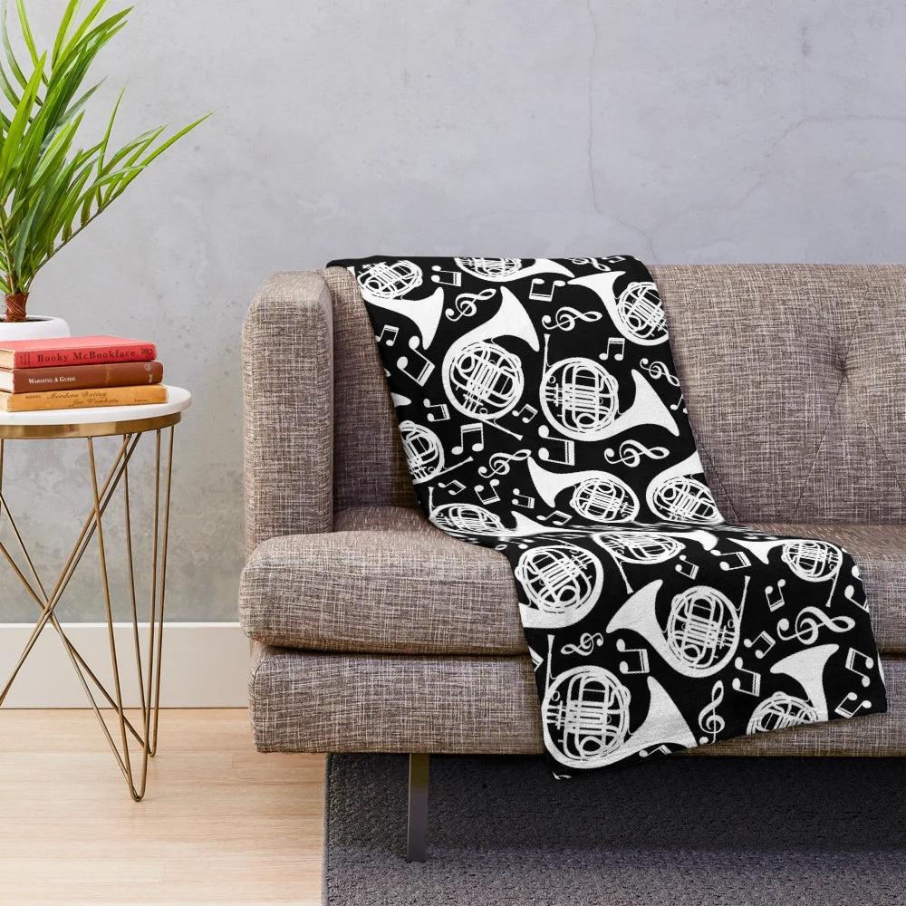 White plush blanket featuring a pattern of french horns and music notes