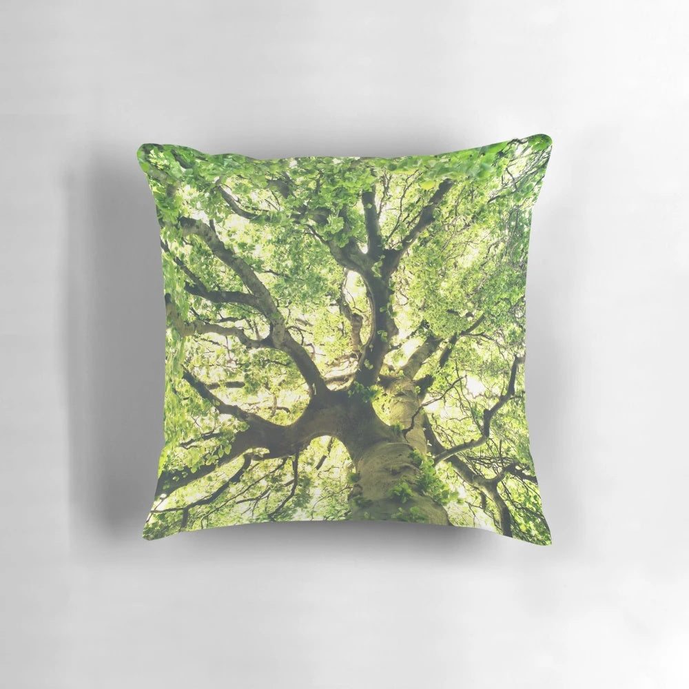 A cozy pillow featuring a magical forest scene with a tree covered in sunlight
