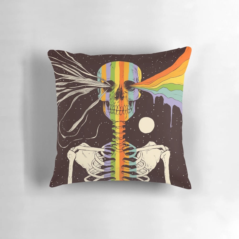 A decorative pillow with a dark, surreal design featuring a skull, skeleton, and celestial elements like stars, moons, and rainbows against a dark background.