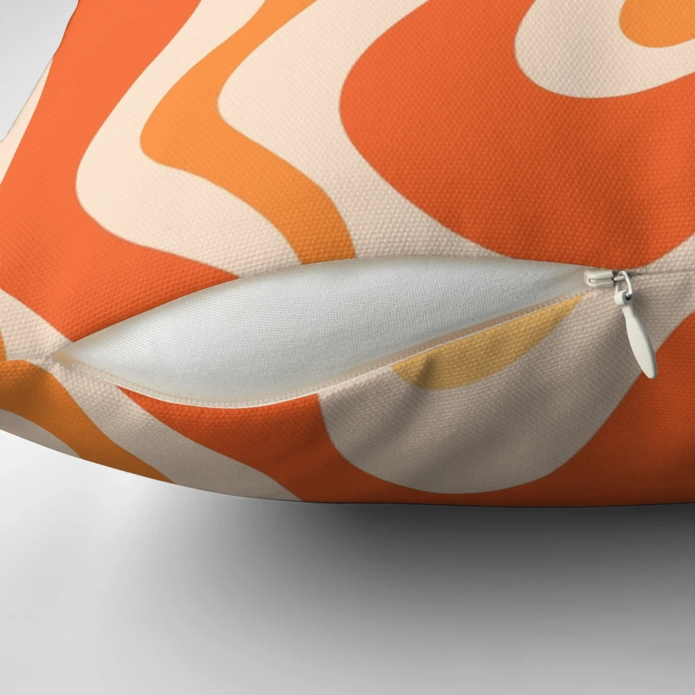 Tangerine-colored abstract swirl pattern on a modern throw pillow
