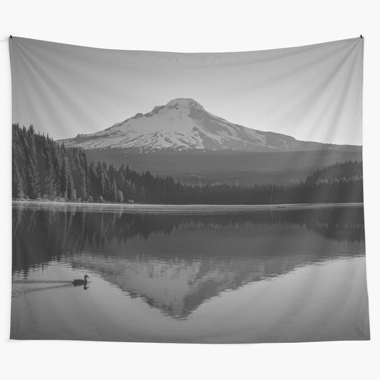 Black and white photograph of a serene mountain lake in a forested landscape