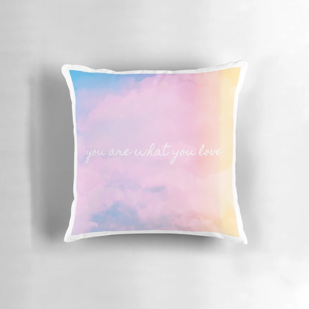 A soft, pink and pastel-colored throw pillow with a sunset and cloud design, inspired by Taylor Swift's aesthetic.
