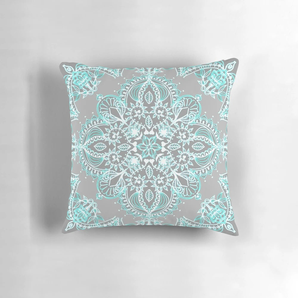 Teal and aqua lace mandala design on a grey decorative pillow
