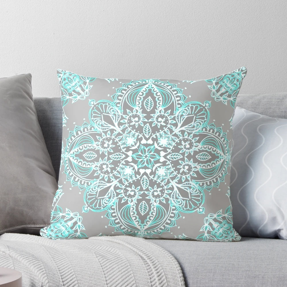 Teal and aqua lace mandala design on a grey decorative pillow