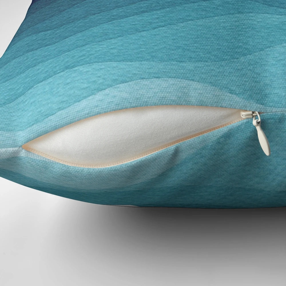 Teal and white pillow with a garland of stars design, depicting a paper boat sailing on the ocean.
