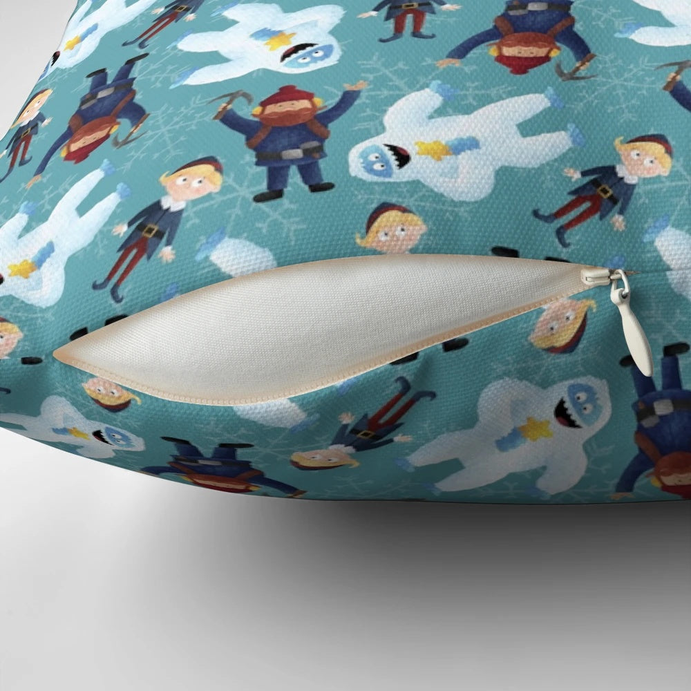 Teal pillow with a winter scene featuring Yukon Cornelius and the Abominable Snowman