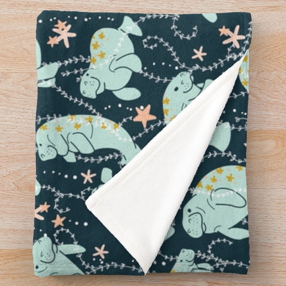 Teal plush blanket featuring a cute manatee illustration