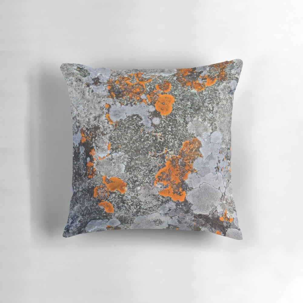Decorative throw pillow featuring a natural lichen and stone texture in a palette of orange, grey, and black.