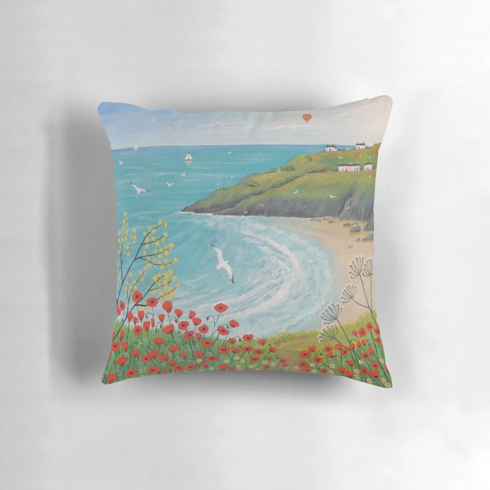 A decorative pillow featuring a serene coastal landscape with vibrant poppies.