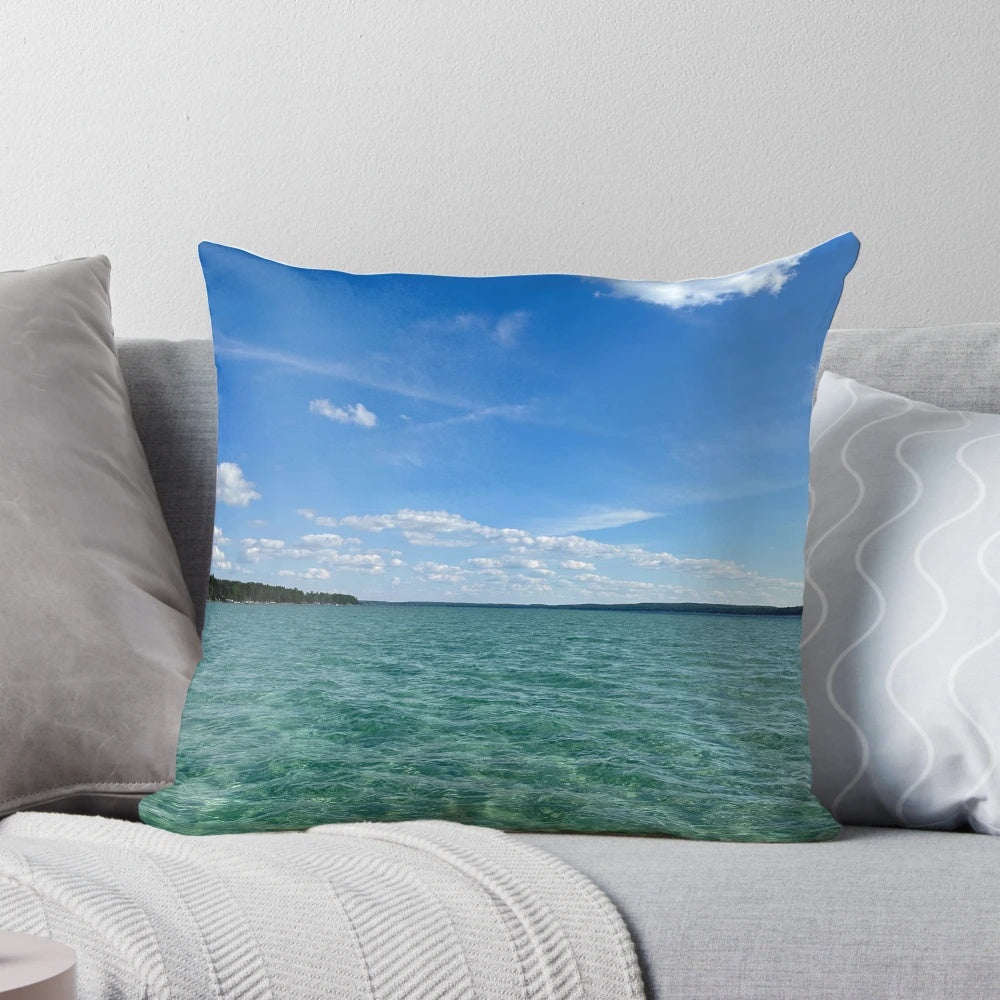 Soft, decorative pillow featuring a beautiful, calming lake scene with blue sky, clouds, and trees.