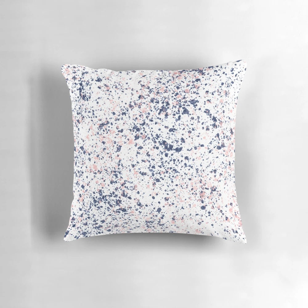 Navy blue and blush pink abstract ink spatter pattern on a white decorative pillow