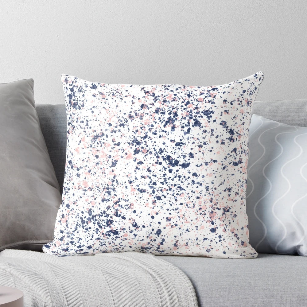 Navy blue and blush pink abstract ink spatter pattern on a white decorative pillow