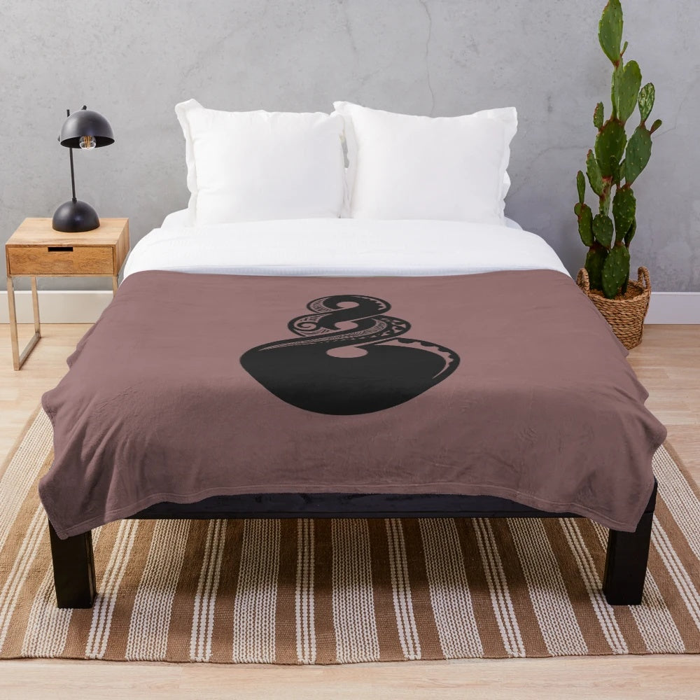 Maori-inspired plush blanket with tribal koru and hei matau pendant design