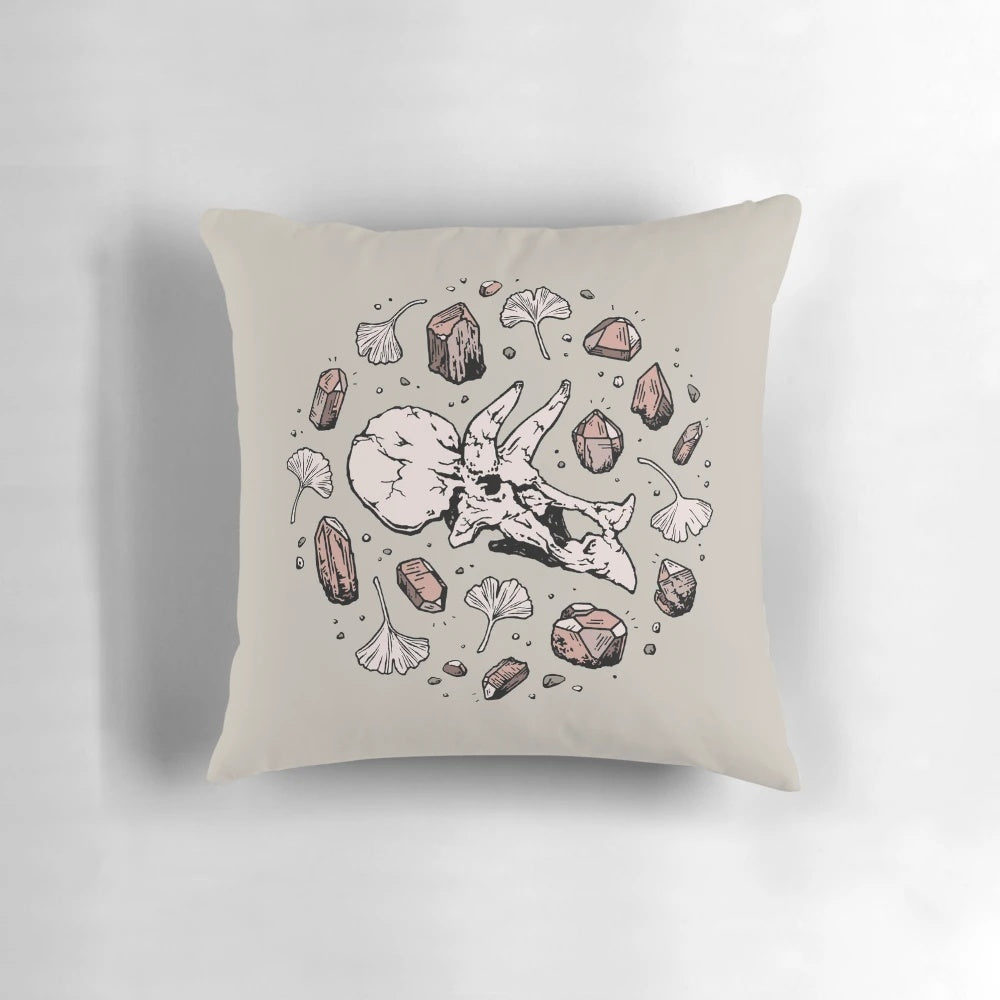Decorative Triceratops dinosaur skull fossil art pillow with rose quartz mineral accent.