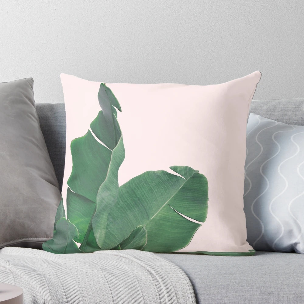 Tropical pillow featuring vibrant banana leaves and lush botanical foliage on a pink background.