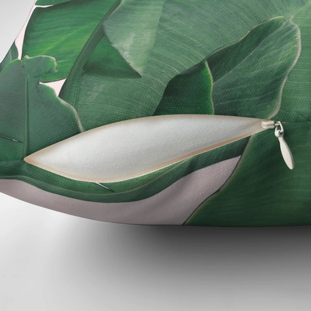Tropical pillow featuring vibrant banana leaves and lush botanical foliage on a pink background.