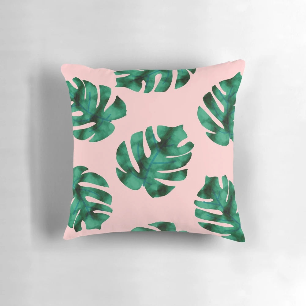 Tropical fern leaves and botanical floral pattern on a peach-colored pillow