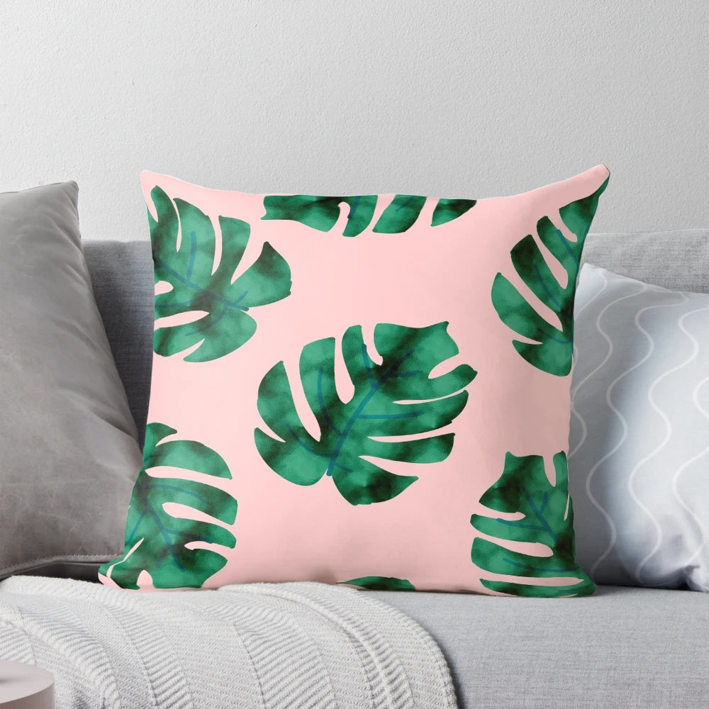 Tropical fern leaves and botanical floral pattern on a peach-colored pillow