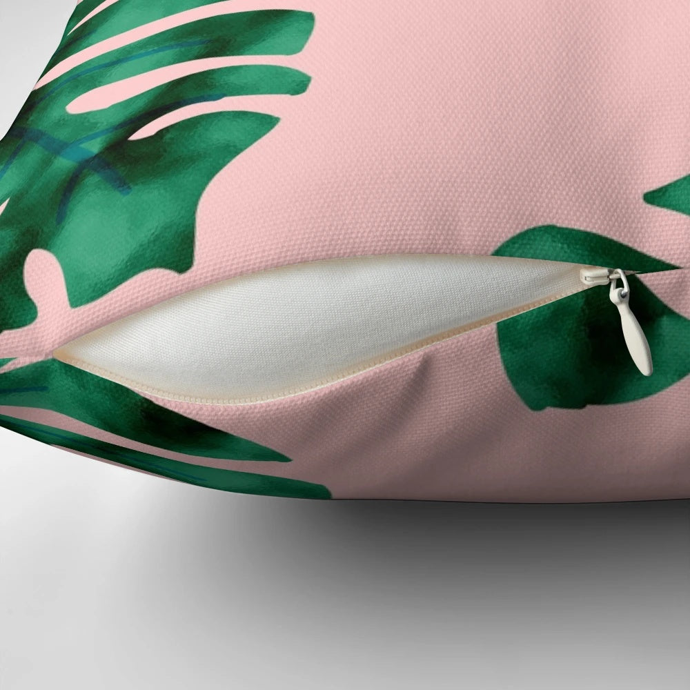 Tropical fern leaves and botanical floral pattern on a peach-colored pillow