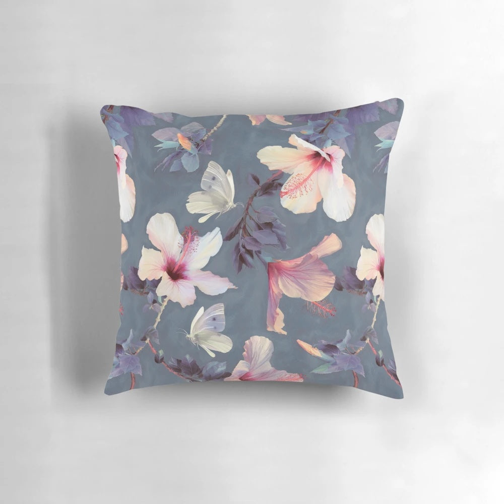 Decorative throw pillow featuring a painted pattern of tropical hibiscus flowers and butterflies in shades of pink, grey, and white.