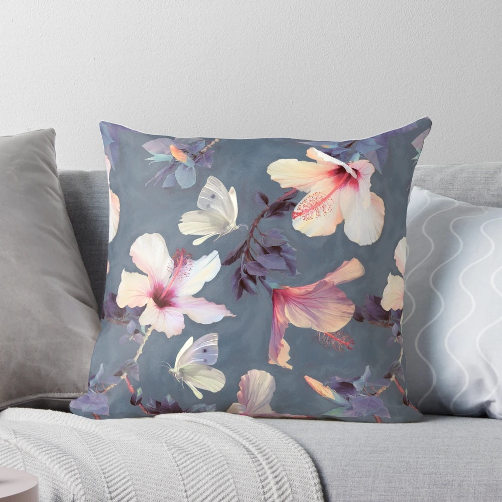 Decorative throw pillow featuring a painted pattern of tropical hibiscus flowers and butterflies in shades of pink, grey, and white.