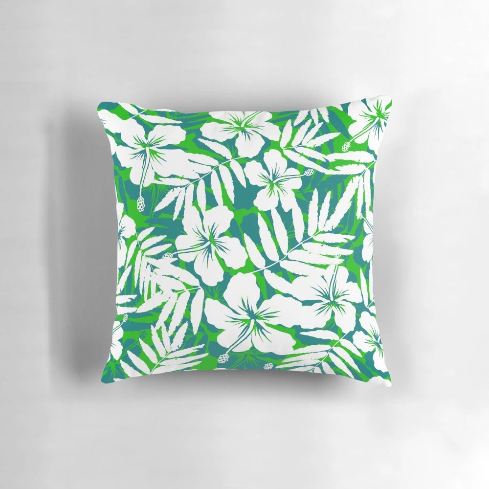 Vibrant tropical flowers with green leaves and white petals in a repeating floral pattern on a decorative throw pillow.