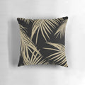 A gold and black tropical palm leaf print pillow, featuring a collage of lush palm fronds and foliage.