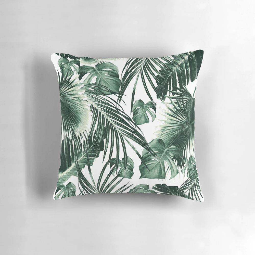 A vibrant, nature-inspired tropical leaves pillow with a collage-style design in shades of green and white.