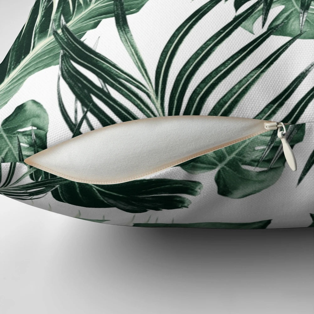 A vibrant, nature-inspired tropical leaves pillow with a collage-style design in shades of green and white.