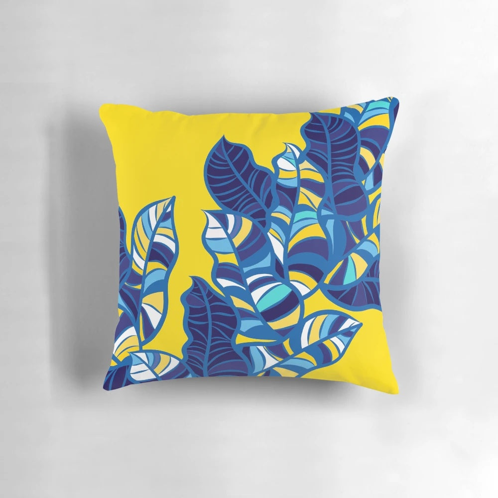 Colorful tropical leaf pattern printed on a yellow throw pillow