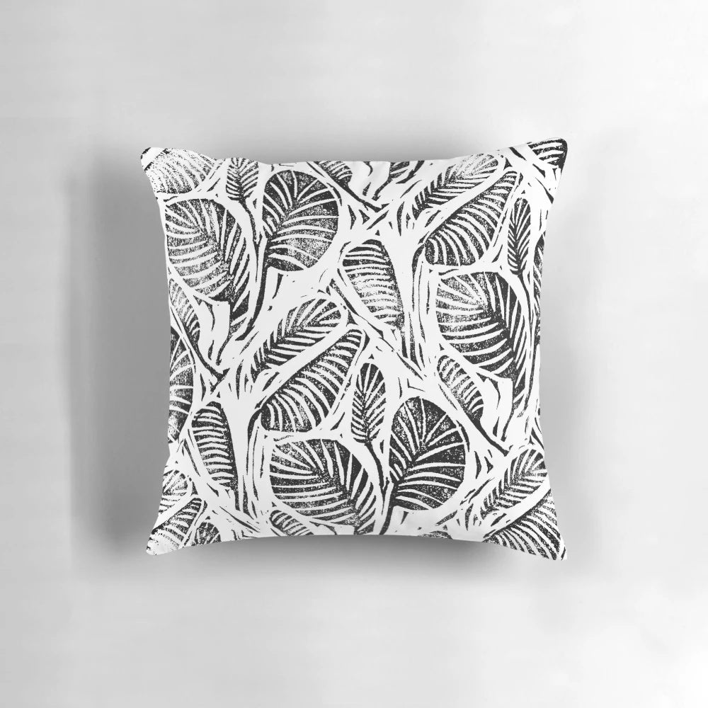 Monochrome linocut print of tropical leaves on a decorative pillow