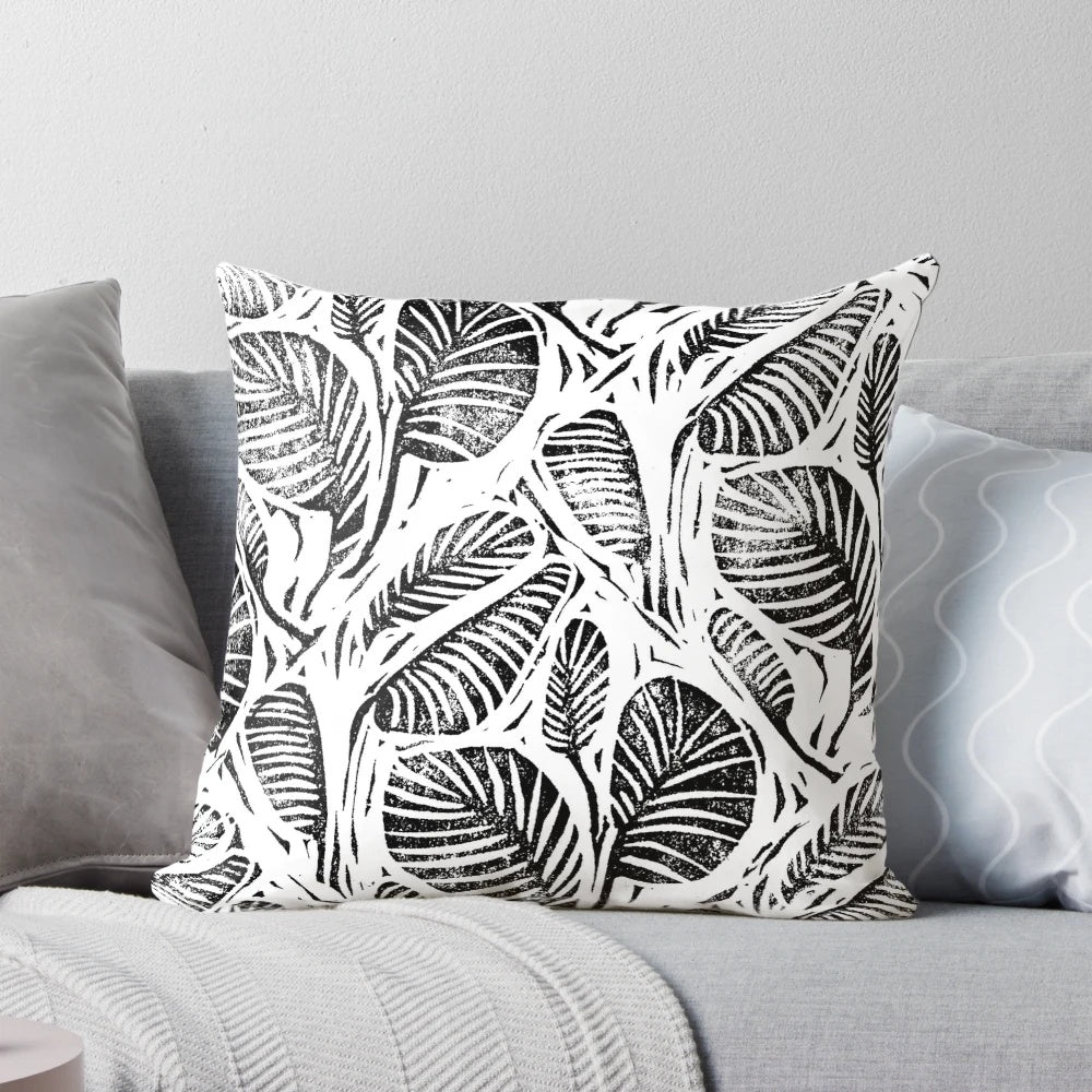 Monochrome linocut print of tropical leaves on a decorative pillow