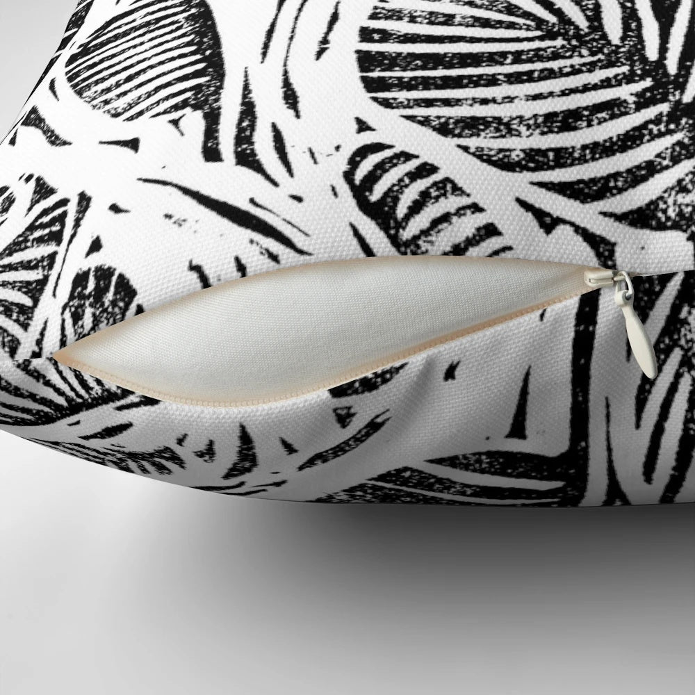 Monochrome linocut print of tropical leaves on a decorative pillow