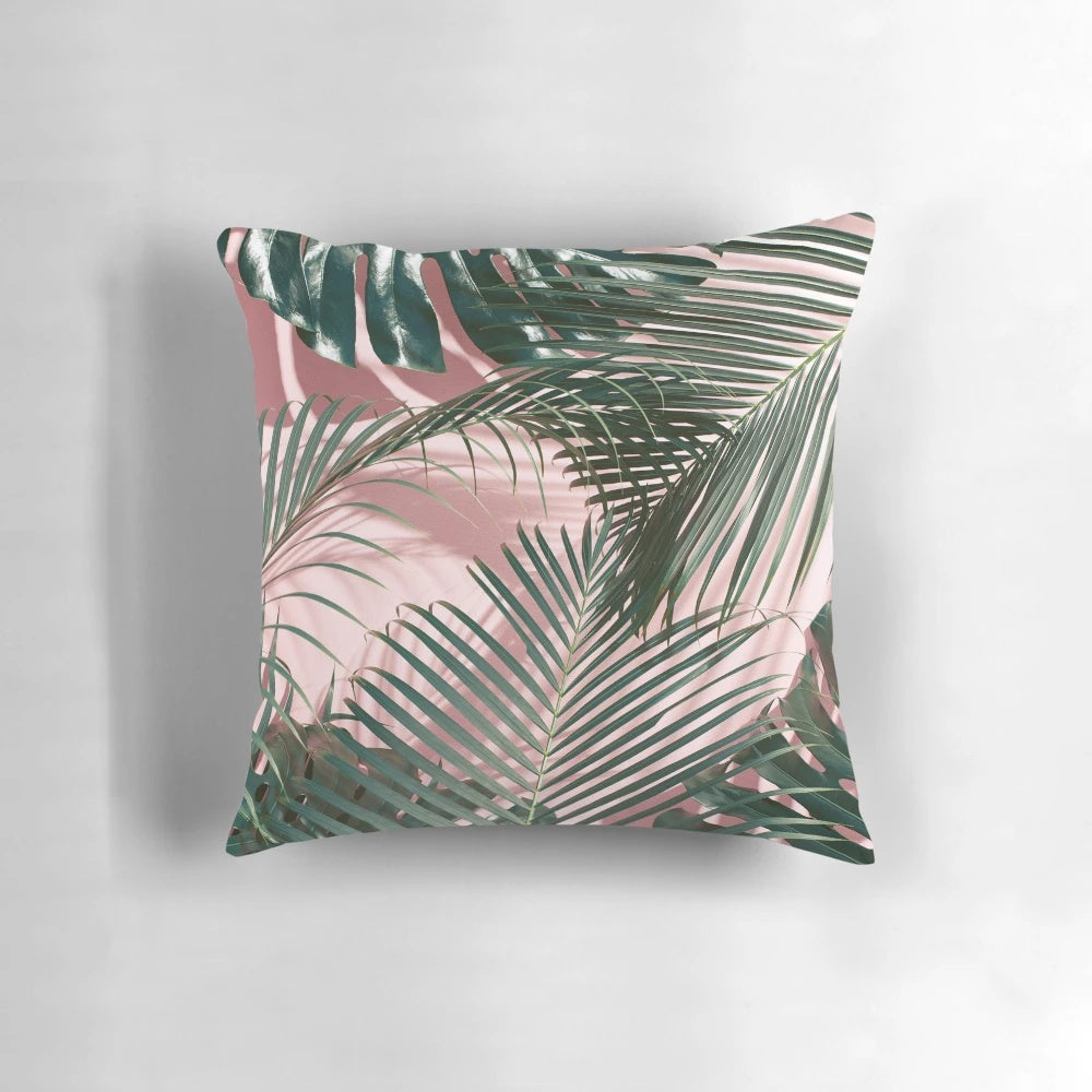 Close-up of a pink and green tropical leaves design on a pillow.