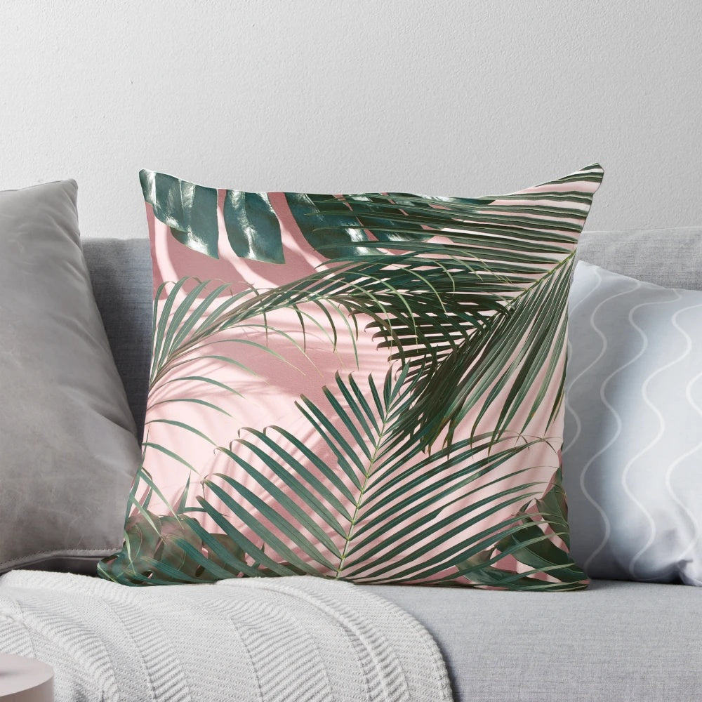 Close-up of a pink and green tropical leaves design on a pillow.