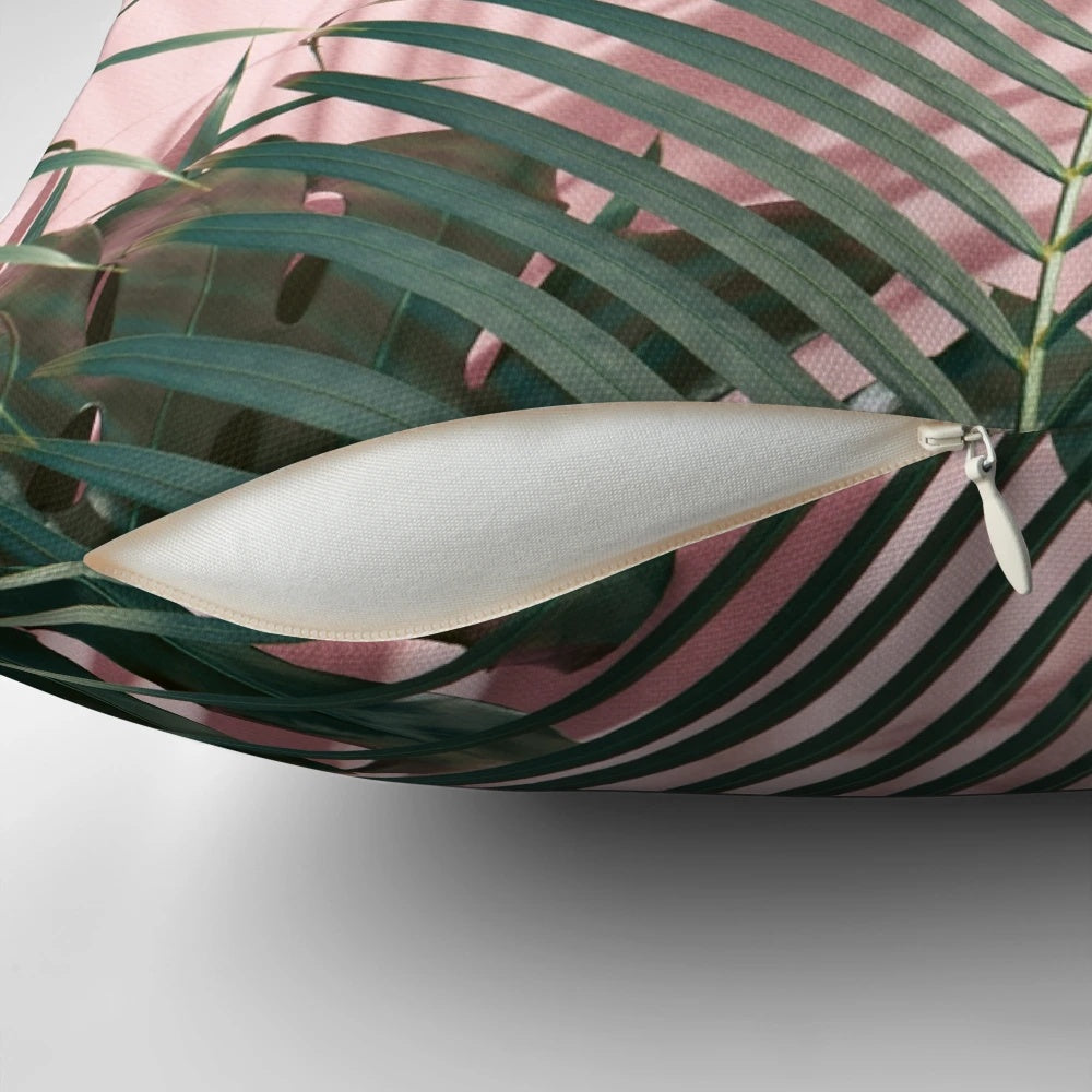 Close-up of a pink and green tropical leaves design on a pillow.