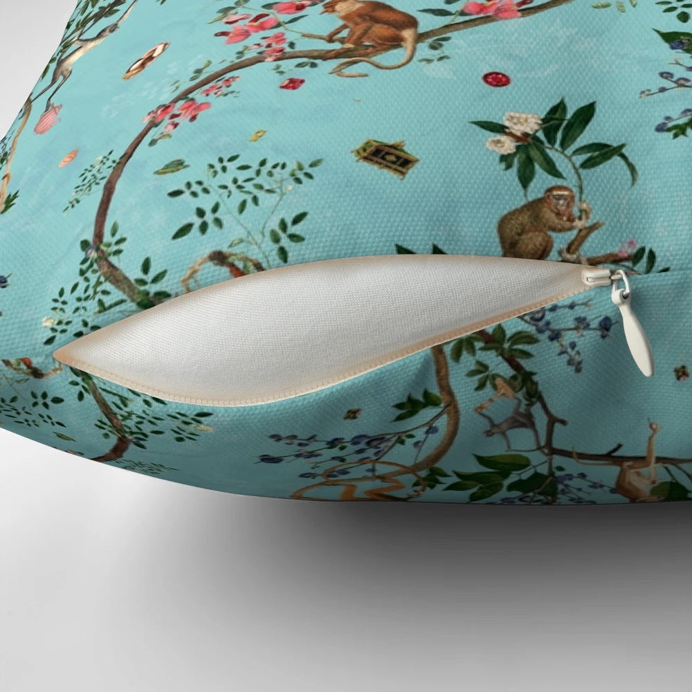 Colorful watercolor-style monkey and floral design on an aqua blue decorative pillow