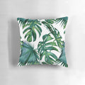 Decorative pillow featuring tropical monstera and palm leaves on a white background