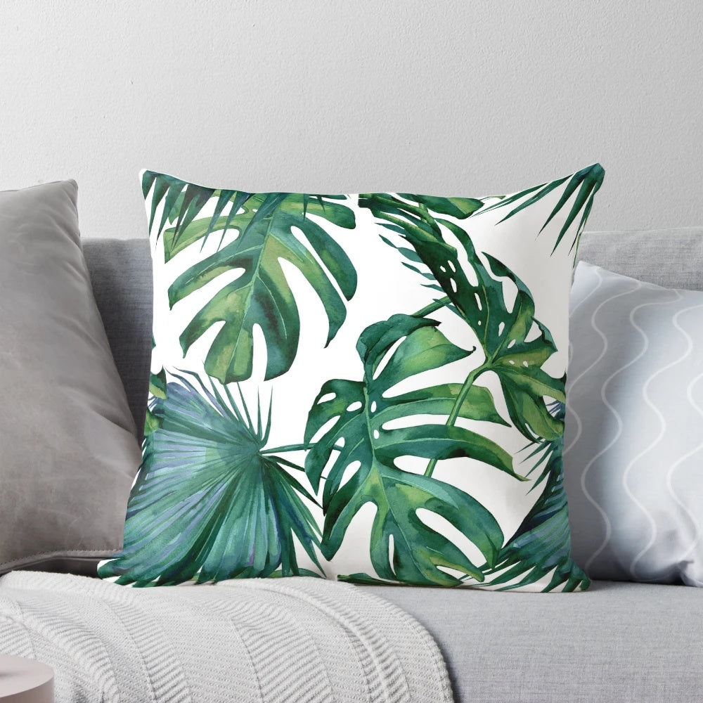 Decorative pillow featuring tropical monstera and palm leaves on a white background