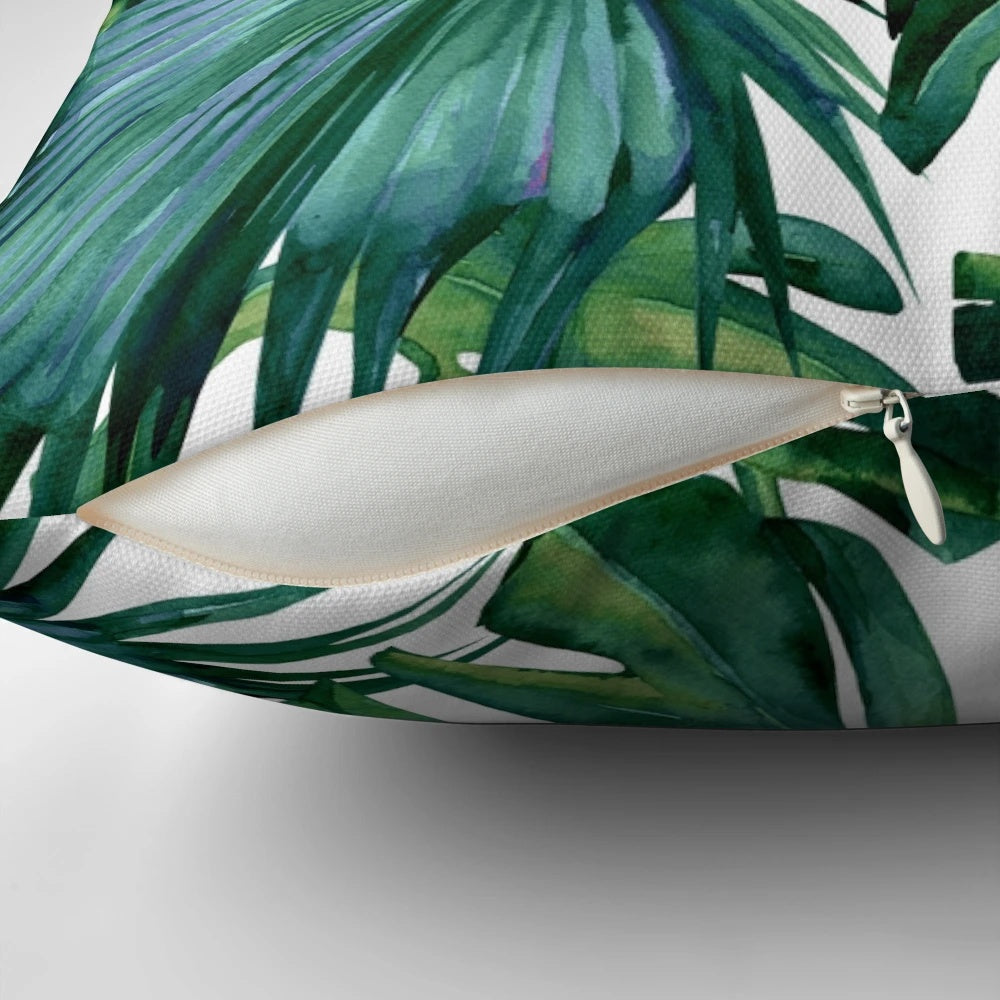 Decorative pillow featuring tropical monstera and palm leaves on a white background